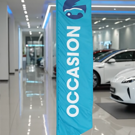 Video du drapeau oriflamme publicitaire bleu turquoise avec inscription 'OCCASION' en lettres blanches et logo automobile, installé dans un showroom de voitures d'occasion. 