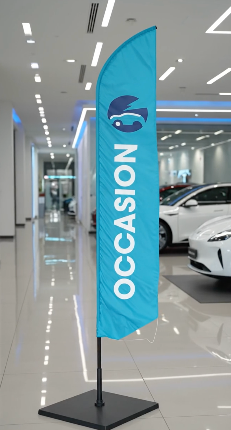 Video du drapeau oriflamme publicitaire bleu turquoise avec inscription 'OCCASION' en lettres blanches et logo automobile, installé dans un showroom de voitures d'occasion. 