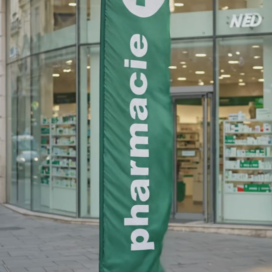 Spot vidéo du drapeau oriflamme publicitaire vert avec inscription 'PHARMACIE' en lettres blanches